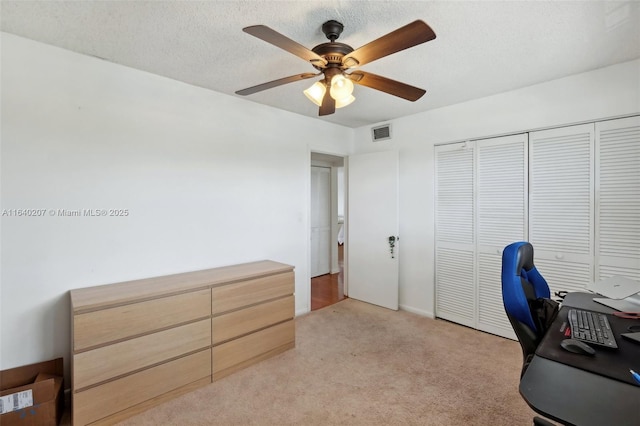 carpeted office space with a textured ceiling and ceiling fan