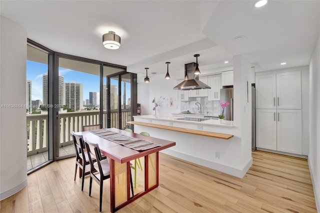 dining space featuring expansive windows, light hardwood / wood-style floors, and sink