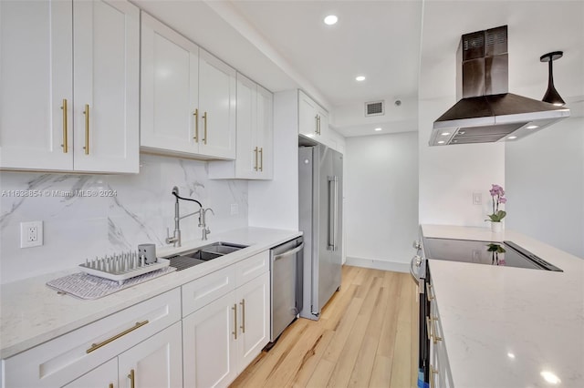 kitchen with appliances with stainless steel finishes, tasteful backsplash, island range hood, sink, and white cabinetry