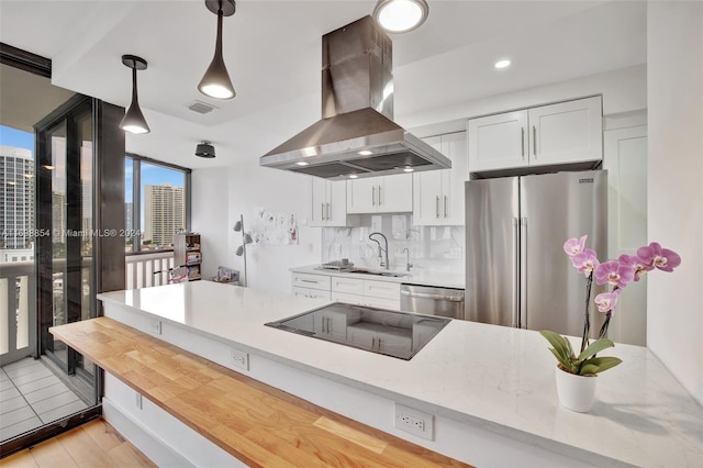 kitchen featuring light stone countertops, stainless steel appliances, white cabinetry, sink, and island range hood