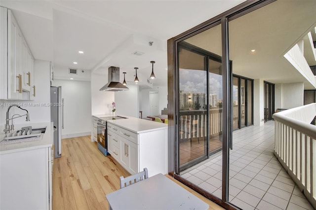 kitchen with light wood-type flooring, stainless steel appliances, sink, island exhaust hood, and white cabinets