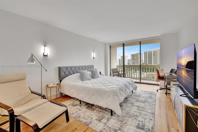 bedroom with access to outside, expansive windows, and light hardwood / wood-style floors