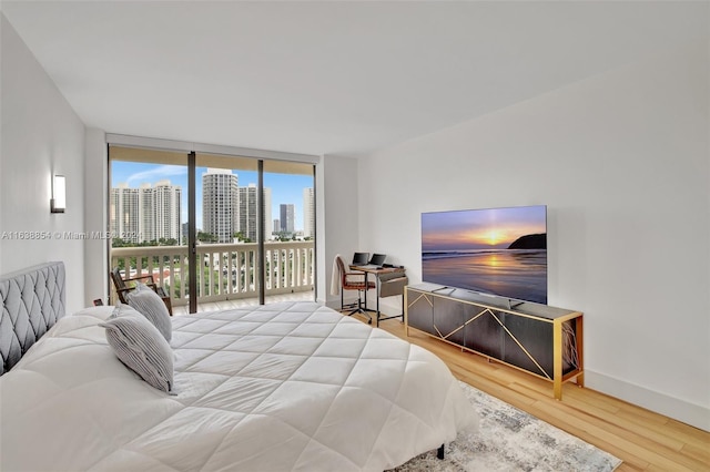 bedroom featuring a wall of windows, light hardwood / wood-style floors, and access to exterior