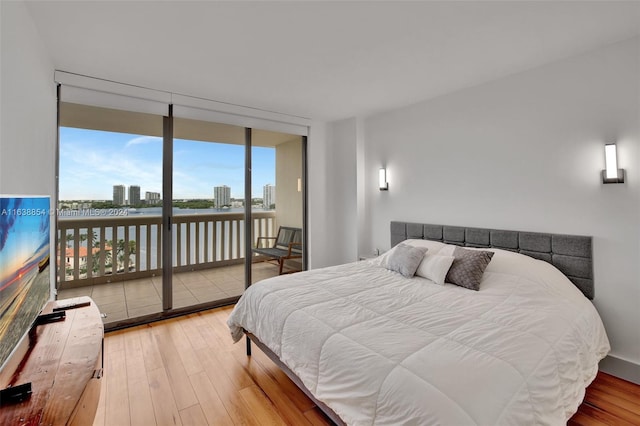 bedroom with access to exterior, expansive windows, and light hardwood / wood-style floors