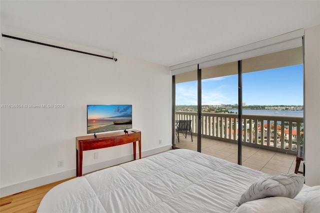 bedroom featuring a wall of windows, access to exterior, and light hardwood / wood-style flooring