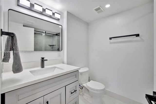 bathroom featuring tiled shower, vanity, and toilet