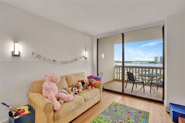 living room featuring a water view, a wall of windows, and light hardwood / wood-style flooring