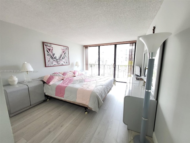 bedroom with expansive windows, a textured ceiling, light hardwood / wood-style floors, and access to exterior