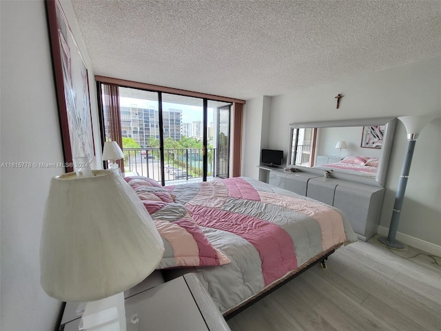 bedroom with light hardwood / wood-style flooring, a textured ceiling, floor to ceiling windows, and multiple windows