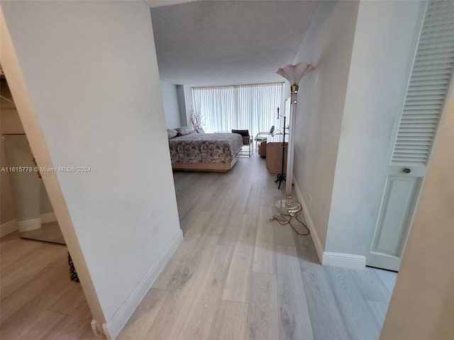 corridor with light hardwood / wood-style flooring and a textured ceiling