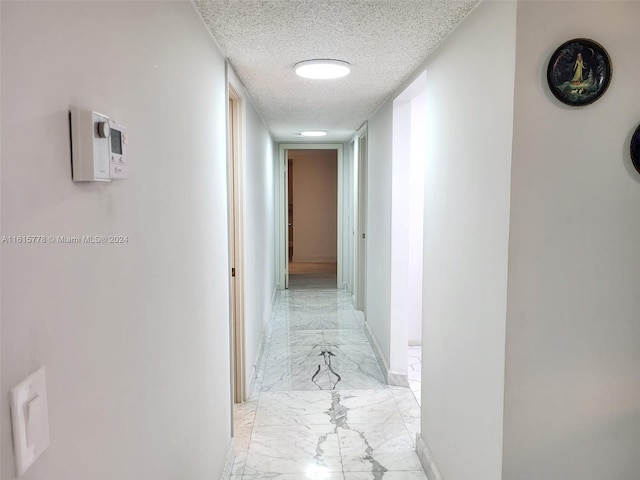 hallway with a textured ceiling and light tile patterned floors