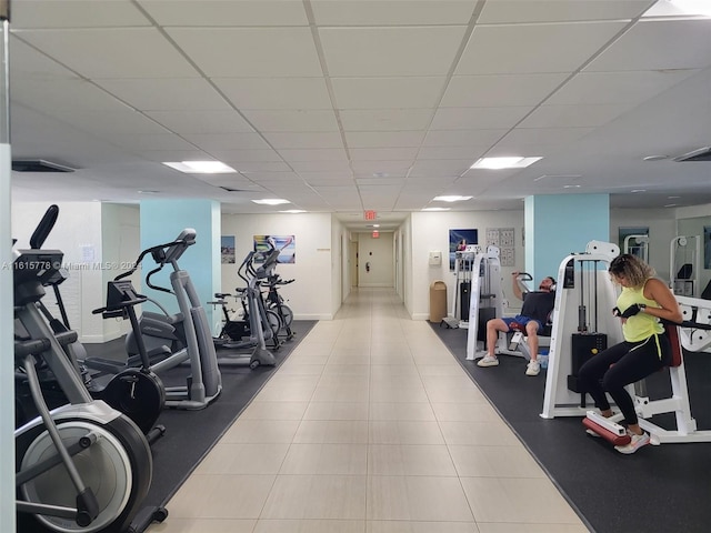 exercise room with a paneled ceiling and light tile patterned floors