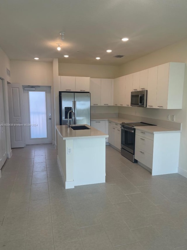 kitchen with appliances with stainless steel finishes, a center island with sink, light tile patterned flooring, sink, and white cabinetry