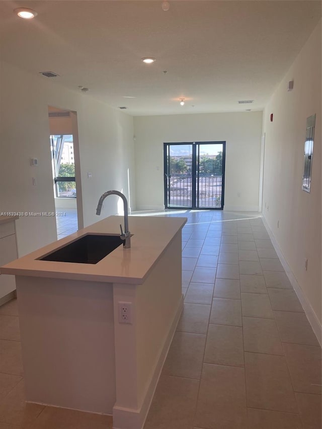 kitchen featuring light tile patterned floors, sink, and an island with sink