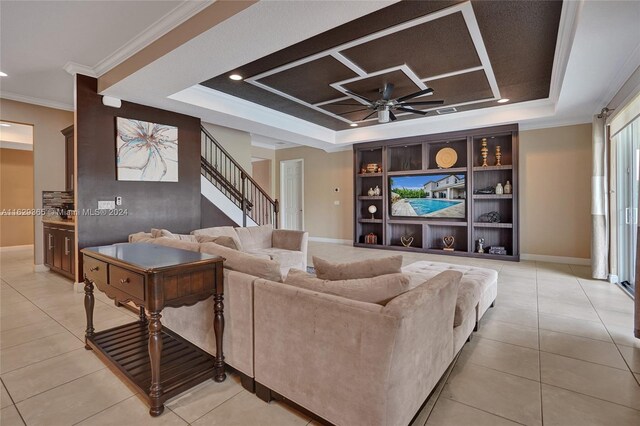 tiled living room with crown molding, ceiling fan, and a raised ceiling