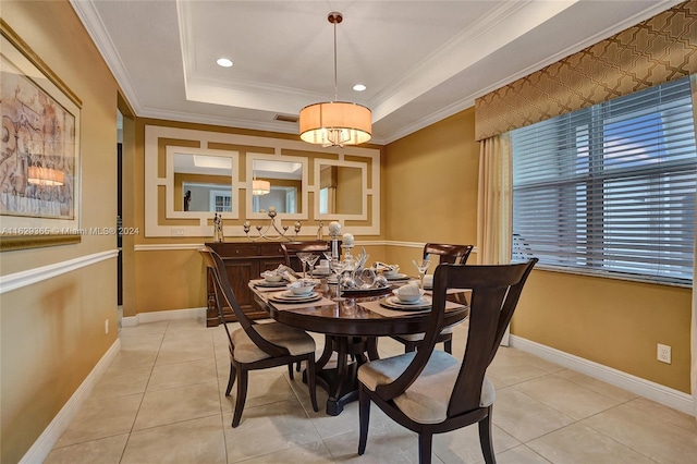 dining area with ornamental molding, light tile patterned floors, and a raised ceiling