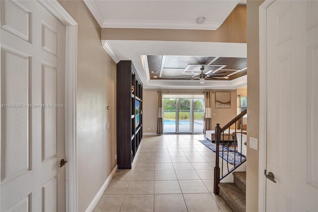 interior space with light tile patterned flooring, a raised ceiling, and crown molding