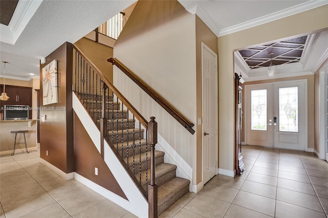 tiled foyer entrance with french doors and ornamental molding