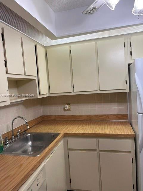 kitchen with tasteful backsplash, sink, white appliances, and white cabinetry