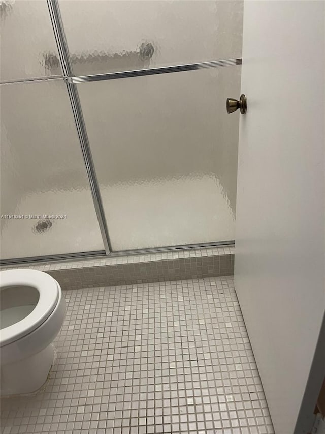 bathroom featuring toilet, tile patterned floors, and an enclosed shower