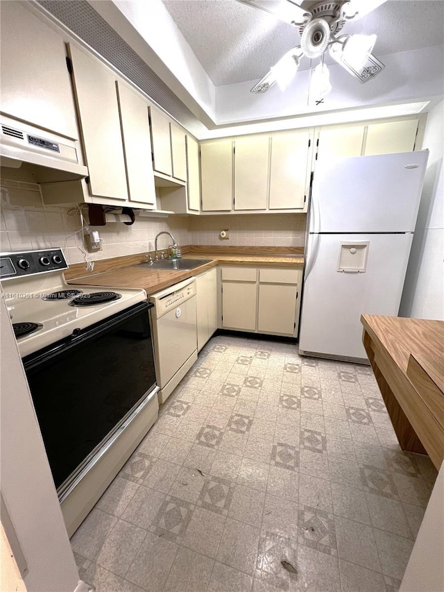 kitchen with sink, decorative backsplash, white appliances, cream cabinets, and a textured ceiling