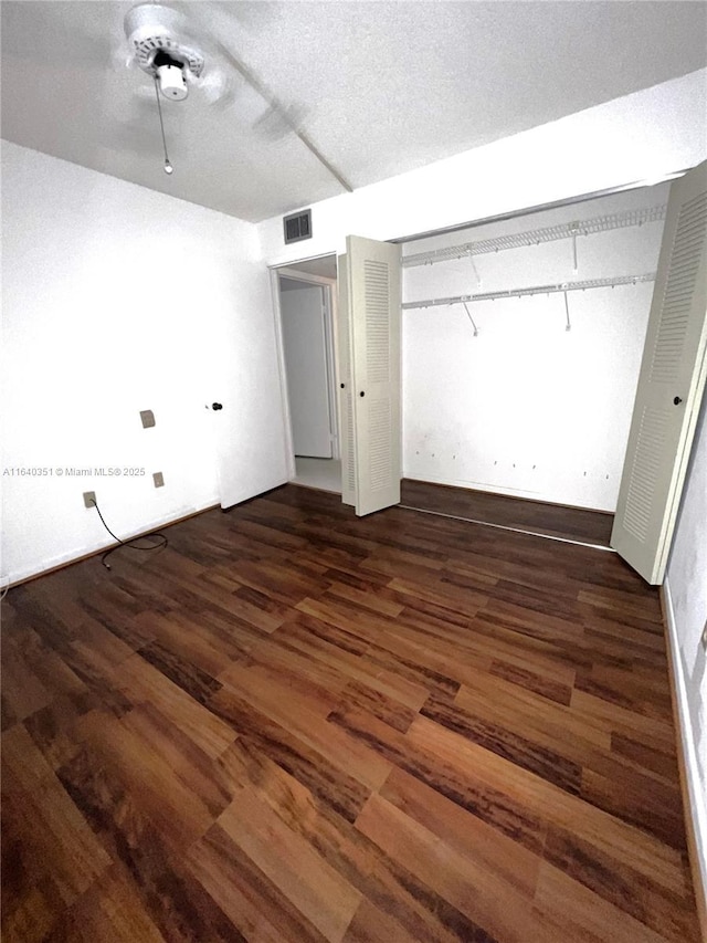 unfurnished bedroom featuring ceiling fan, dark hardwood / wood-style floors, a closet, and a textured ceiling
