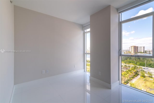 tiled spare room with a wall of windows and a healthy amount of sunlight