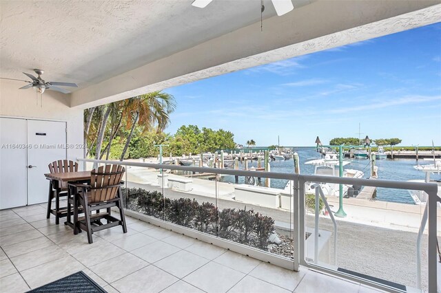 balcony featuring a boat dock, a water view, and ceiling fan