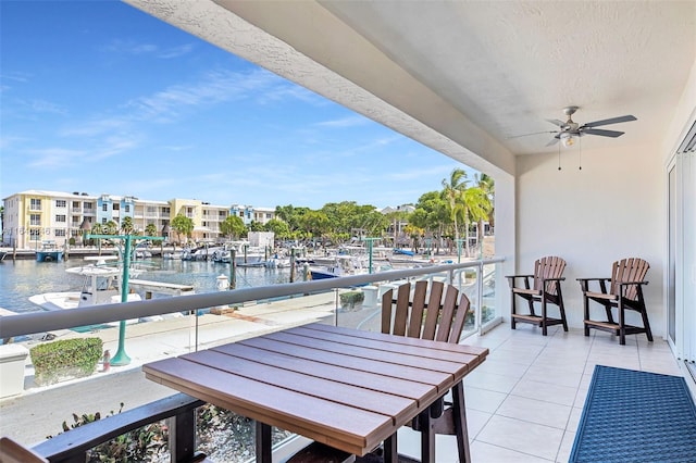 balcony with a boat dock, a water view, and ceiling fan