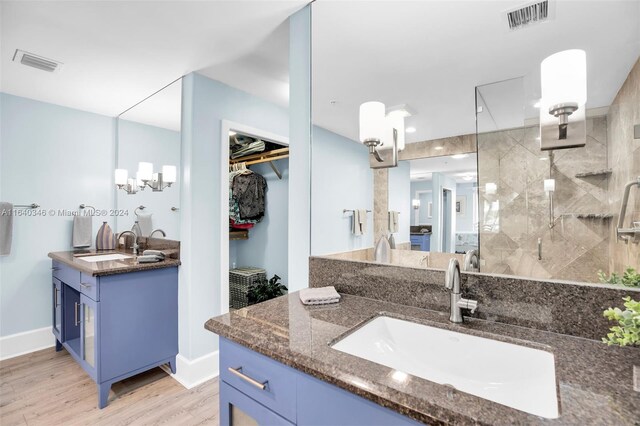 bathroom featuring a tile shower, double sink vanity, and hardwood / wood-style floors