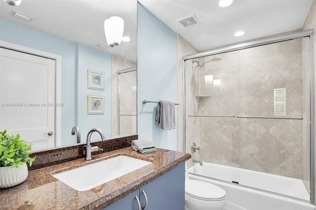 full bathroom with toilet, bath / shower combo with glass door, and vanity