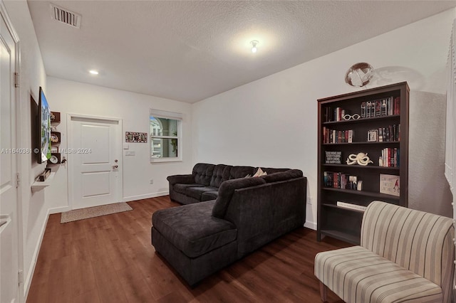 living room featuring a textured ceiling and dark hardwood / wood-style floors