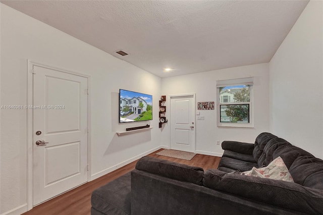 living room with a textured ceiling and dark hardwood / wood-style floors