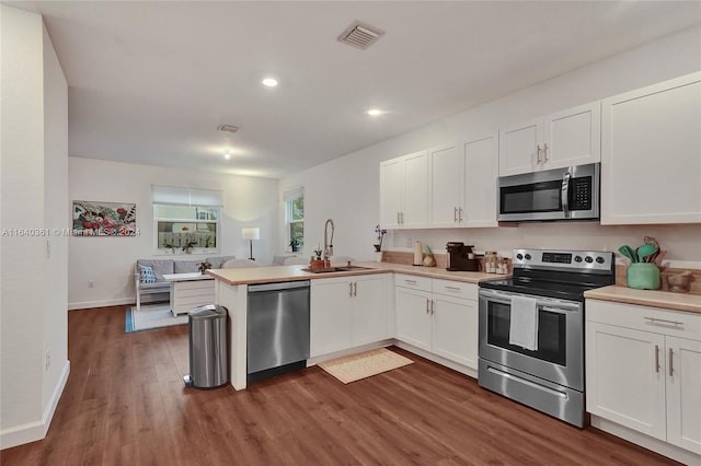 kitchen featuring white cabinets, kitchen peninsula, stainless steel appliances, and dark hardwood / wood-style floors