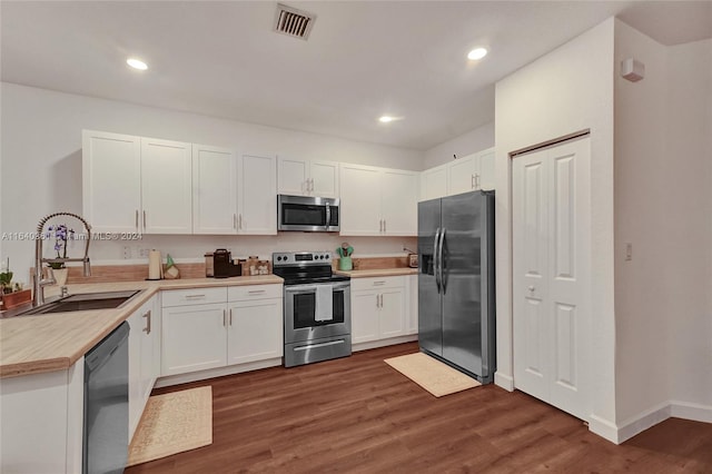 kitchen featuring sink, appliances with stainless steel finishes, dark hardwood / wood-style floors, white cabinets, and wood counters