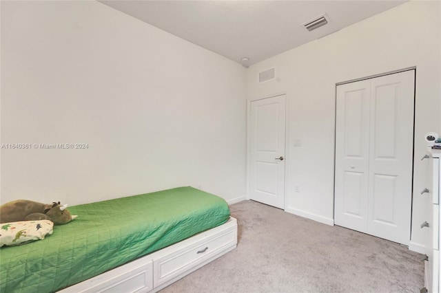 bedroom featuring light colored carpet and a closet