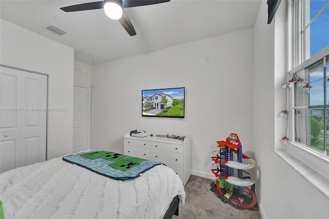 bedroom featuring light colored carpet, multiple windows, ceiling fan, and a closet