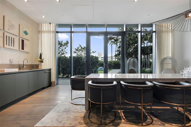 interior space with gray cabinets, expansive windows, sink, and light hardwood / wood-style floors