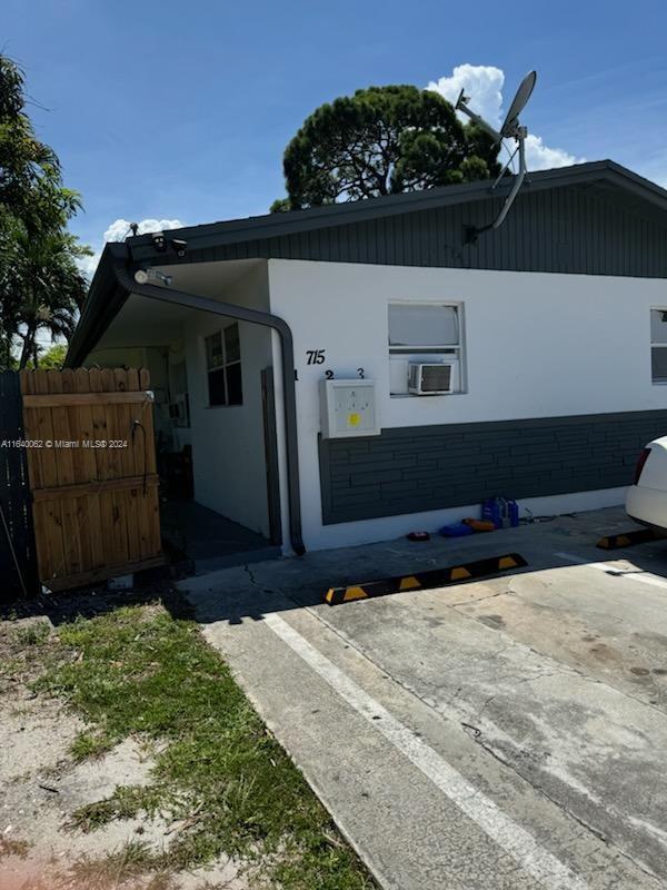 view of side of property featuring cooling unit, stucco siding, and fence