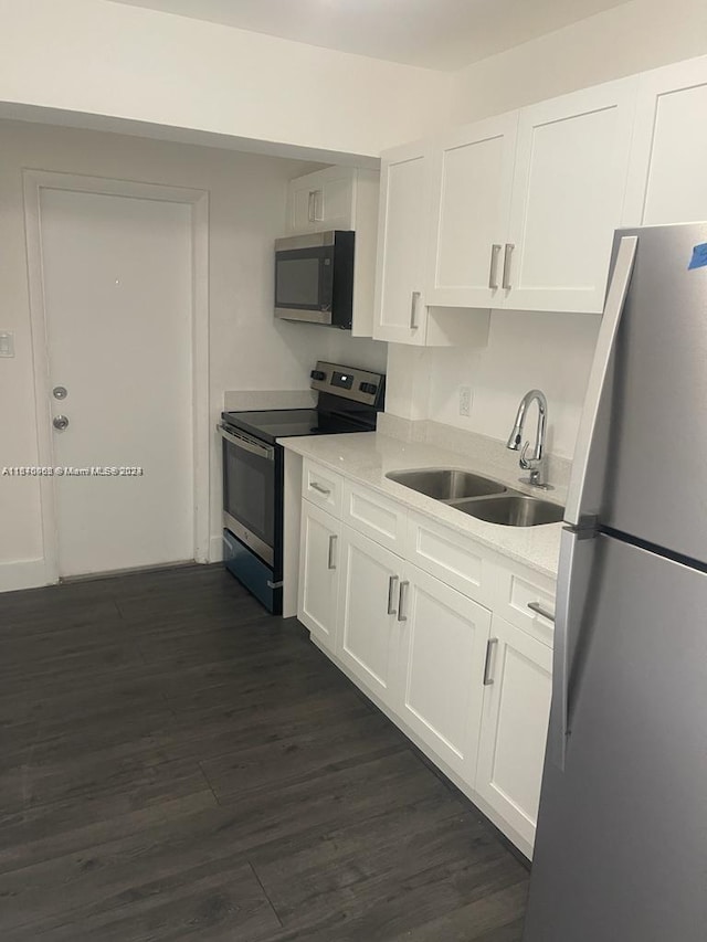 kitchen featuring white cabinetry, stainless steel appliances, dark wood-type flooring, and a sink