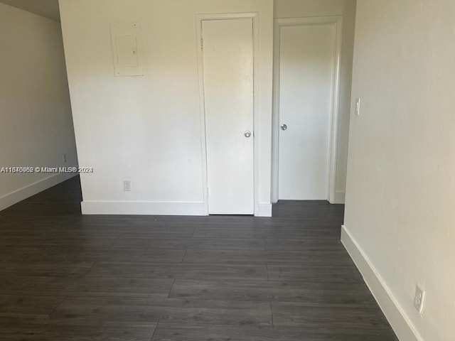 unfurnished room with dark wood finished floors, electric panel, and baseboards