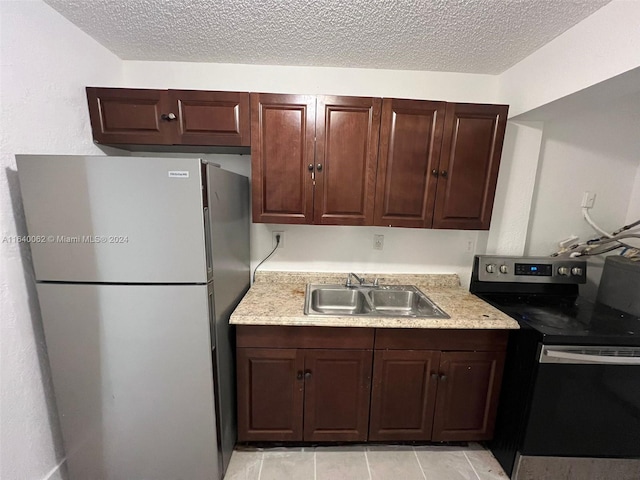 kitchen featuring freestanding refrigerator, electric range, light countertops, a sink, and a textured ceiling