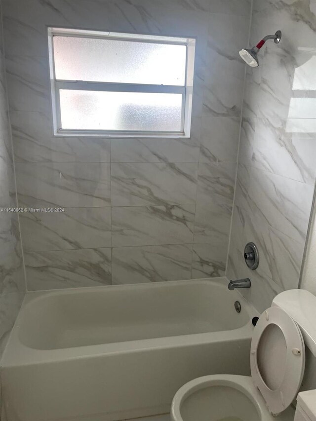 bathroom featuring toilet and tiled shower / bath combo