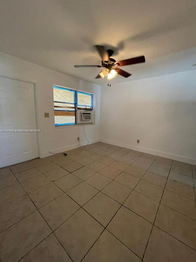 tiled empty room featuring cooling unit, a ceiling fan, a textured ceiling, and baseboards