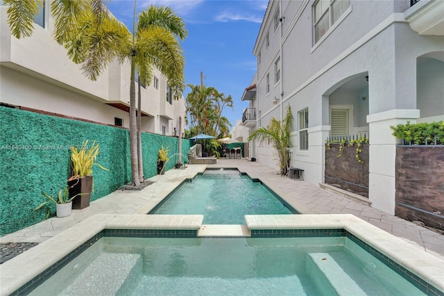 view of pool featuring a pool with connected hot tub and fence