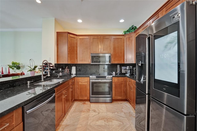 kitchen with brown cabinets, stainless steel appliances, tasteful backsplash, a sink, and dark stone countertops