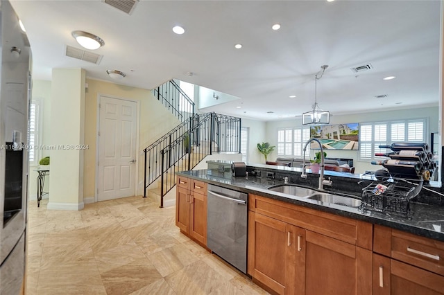 kitchen with hanging light fixtures, dishwasher, sink, light tile patterned flooring, and dark stone counters