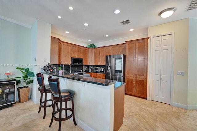 kitchen featuring backsplash, light tile patterned floors, kitchen peninsula, and stainless steel fridge