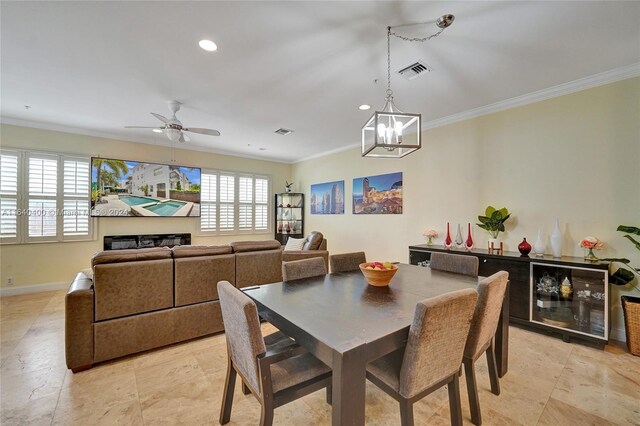 dining area with light tile patterned flooring, ceiling fan with notable chandelier, and crown molding