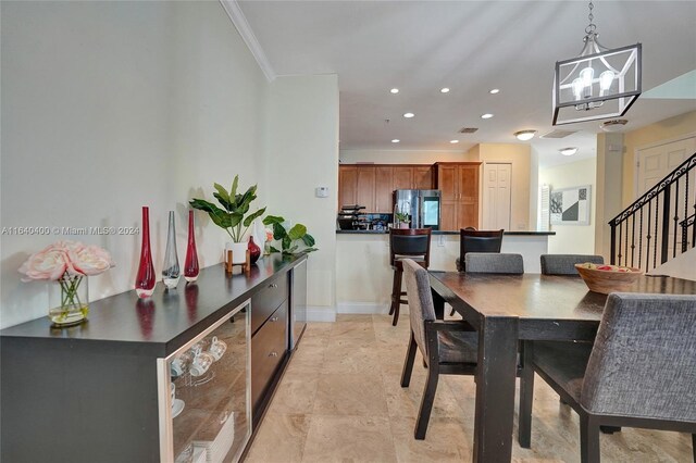 dining area with light tile patterned flooring, beverage cooler, an inviting chandelier, and crown molding